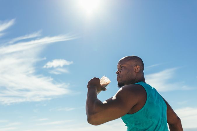 Headshot of man wearing vest drinking a health drink during workout