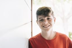 Portrait of a cheerful male teen outside in sunny yard with copy space