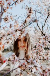 Young happy woman between trees in garden