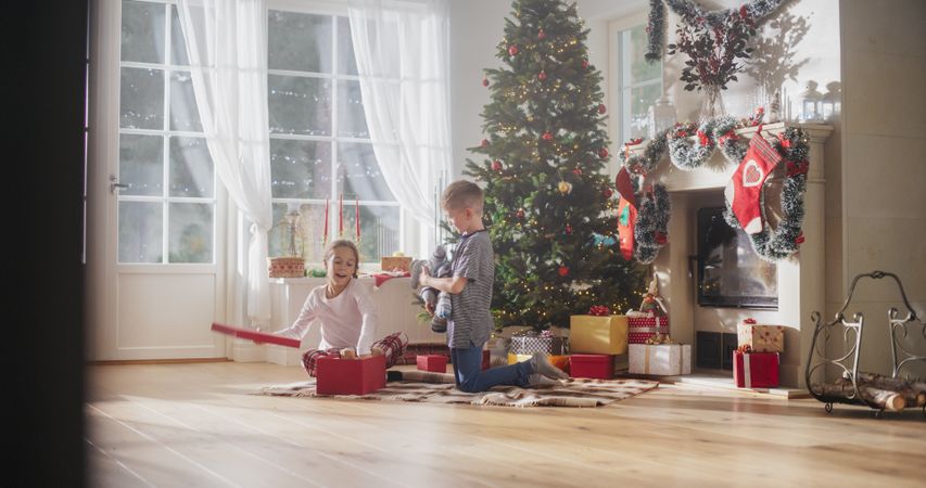Cute Children Impatient to Get Their Gifts from Under the Christmas Tree at Home.