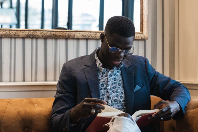 Pensive Black businessman reading book in cafe