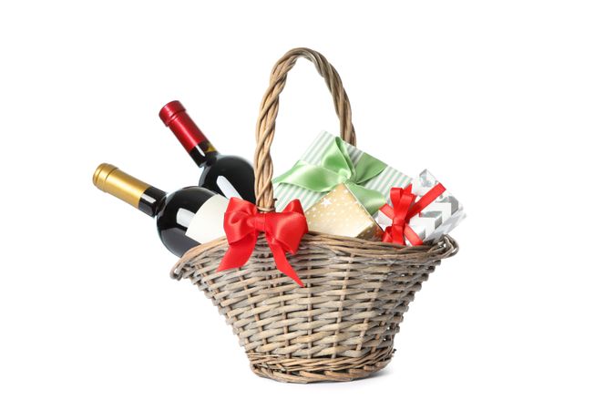 Wicker basket with bottles of wine and presents isolated on light background