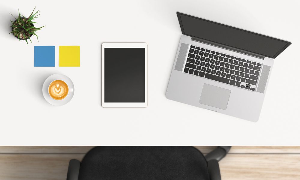 Modern workplace with laptop, coffee cup and smartphone or tablet copy space on table background. Top view. Flat lay style.