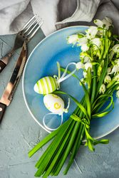 Top view of table setting for Easter dinner with egg decor and flowers