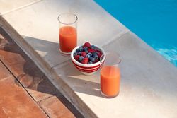 Healthy summer breakfast with fruit and juice by the pool, wide banner format with copy space