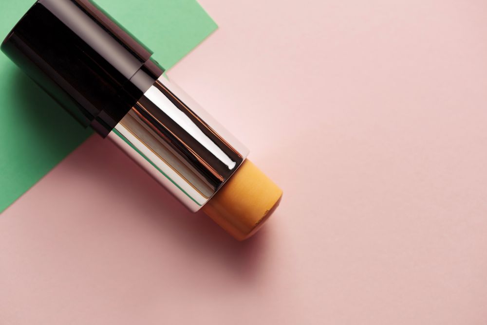 Concealer stick on modern background with geometric shapes.