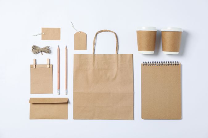 Flat lay composition with blank stationery, paper cups and bag on plain background, mockup