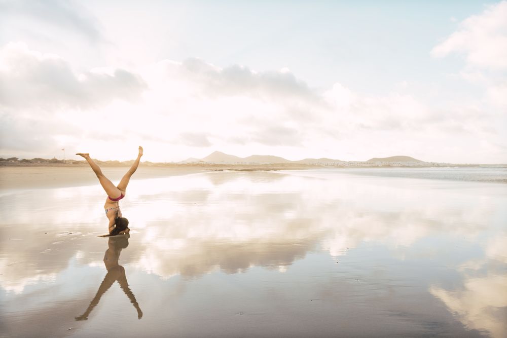 Woman doing handstand near sea