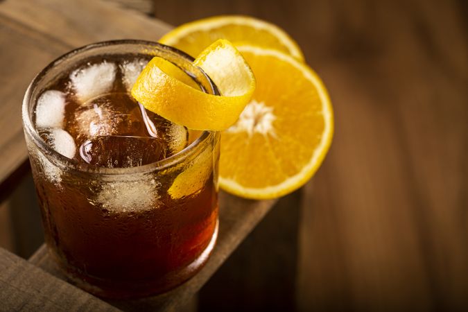 Negroni cocktail with orange, on wooden background.