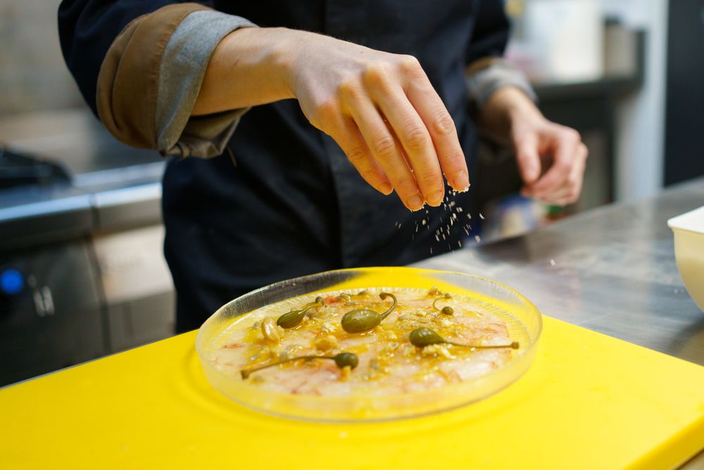 Hands sprinkling salt on delicate appetizer
