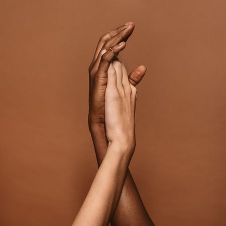 Close up of two female hands together on brown background