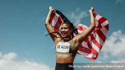 Athlete holding the American flag over the head and smiling 0PAOa5