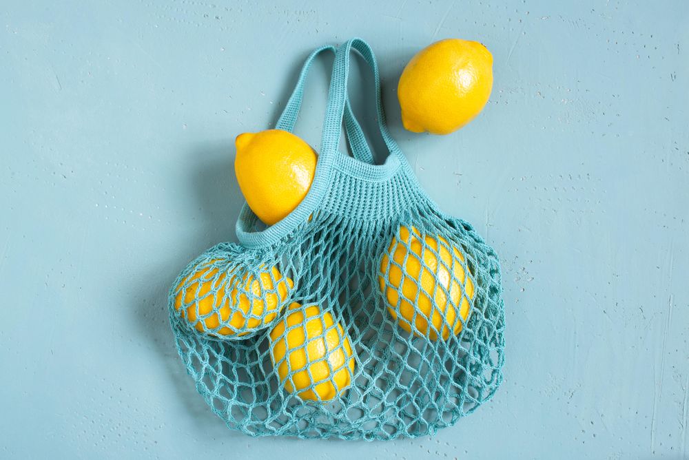 Bright yellow lemons in blue mesh bag