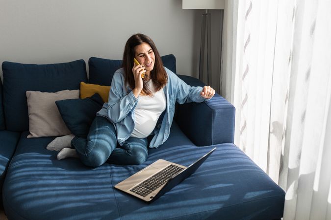 Pregnant woman talking on smartphone during remote work