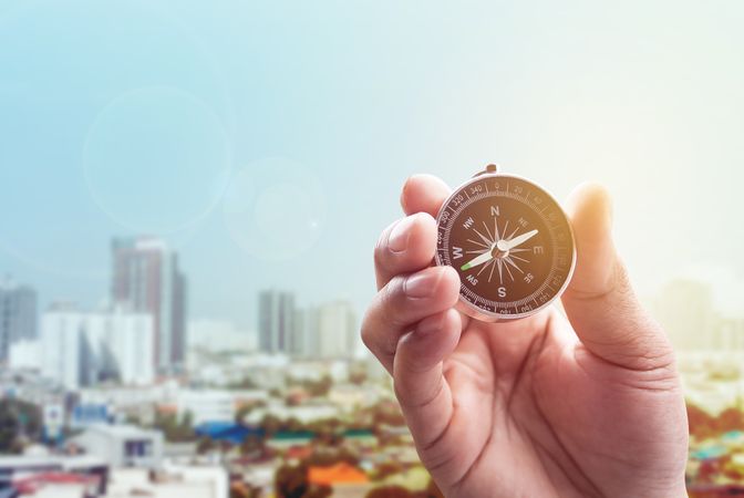 compass in hand on town of blurred blue color with lighting flare