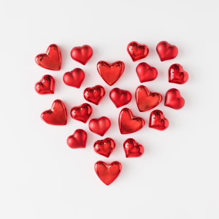 Heart made of red foil hearts on light background