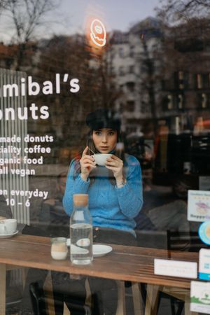 stylish woman drinking coffee into a coffee shop looking away