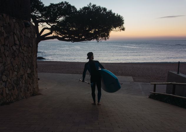 Man practicing paddle surfing with neoprene in a sunrise
