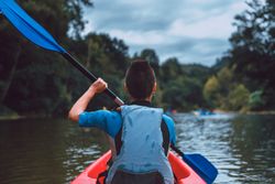 Female kayaking with paddle in raised hands