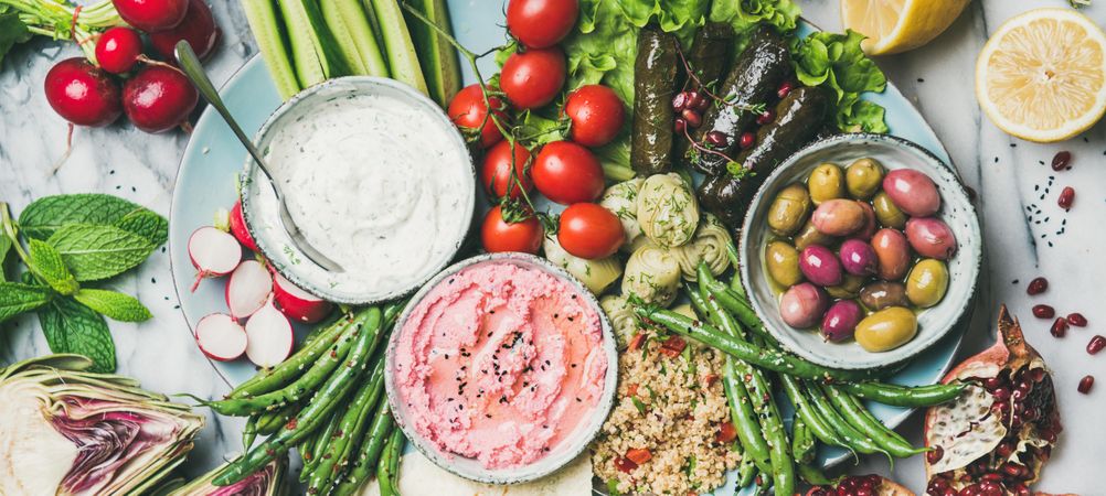 Fresh tray of snacks of fresh vegetables, olives, hummus, and dolmas