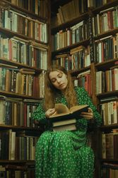 Girl reading a book and sitting beside bookshelves