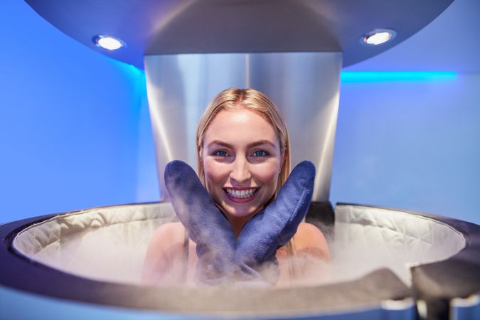 Blonde woman in cryotherapy chamber with gloves on her hand