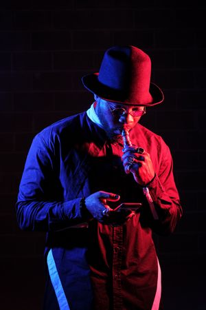 Stylish Black man vaping and browsing smartphone