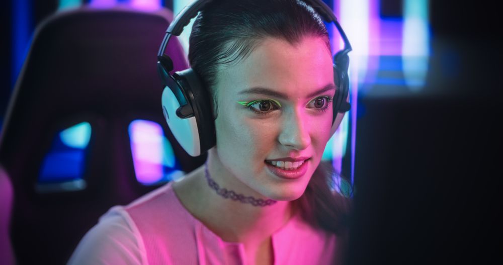 Portrait of a Young Female Wearing Headphones, Talking with Friends and Followers on a Computer.