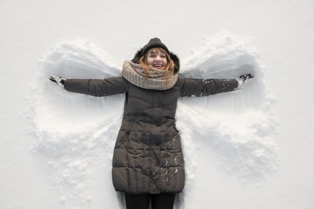 Woman in winter wear making snow angel
