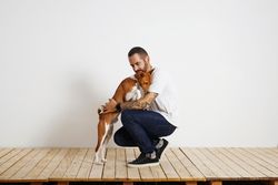Man crouching down to hug dog