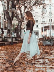 Young ballerina stretching toe in autumn park