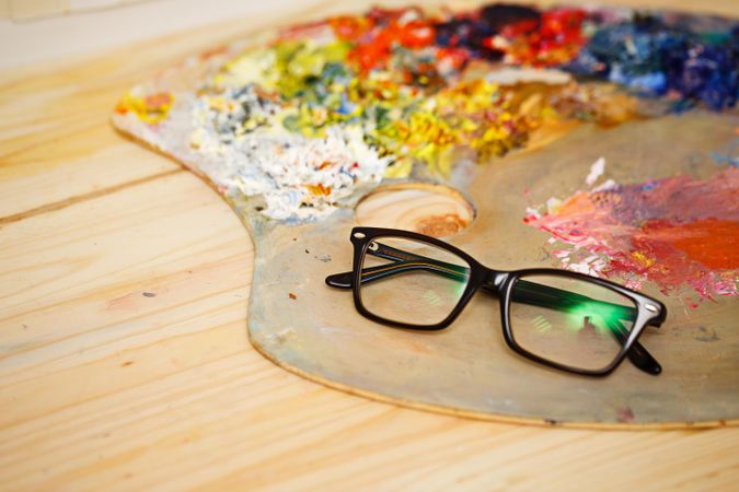 Optical frames lying on paint palette with rich colors