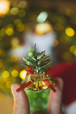 Cropped image of two fingers holding a Christmas bell ornament