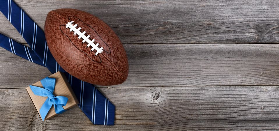 Father’s day celebration with American football and gifts on wooden background
