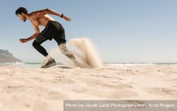 Man doing sprints on sand near the beach bxyer0