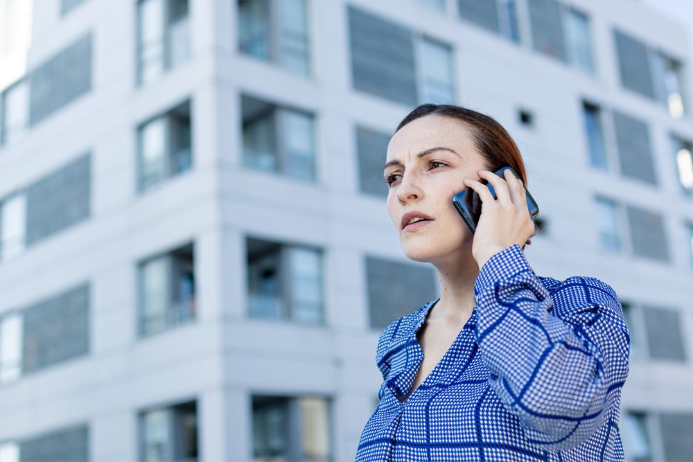 Serious manager speaking on phone on street