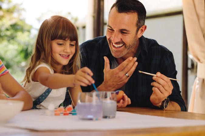 Father and daughter painting easter eggs together