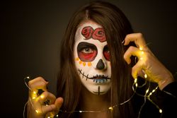 Young woman with creepy face paint holding fairy lights