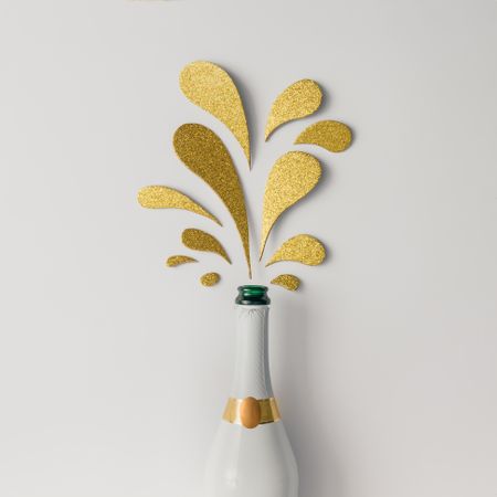 Champagne bottle with golden glittering splashes on light background