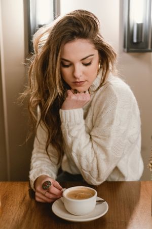 Elegant woman mixing coffee in cafe