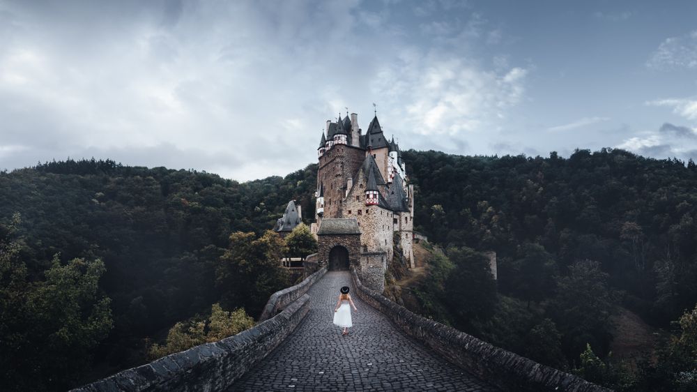 Woman in light dress walking towards Eltz Castle