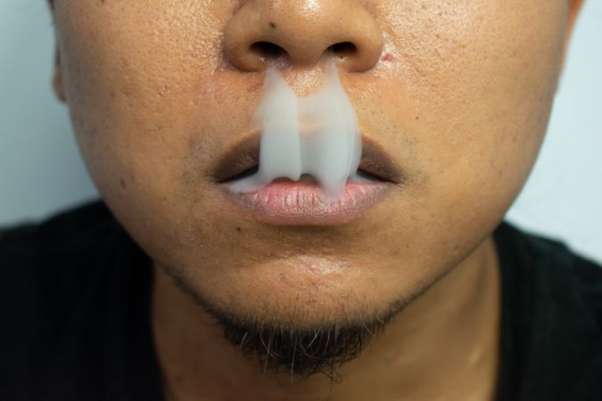 Unrecognizable person exhaling cigarette smoke