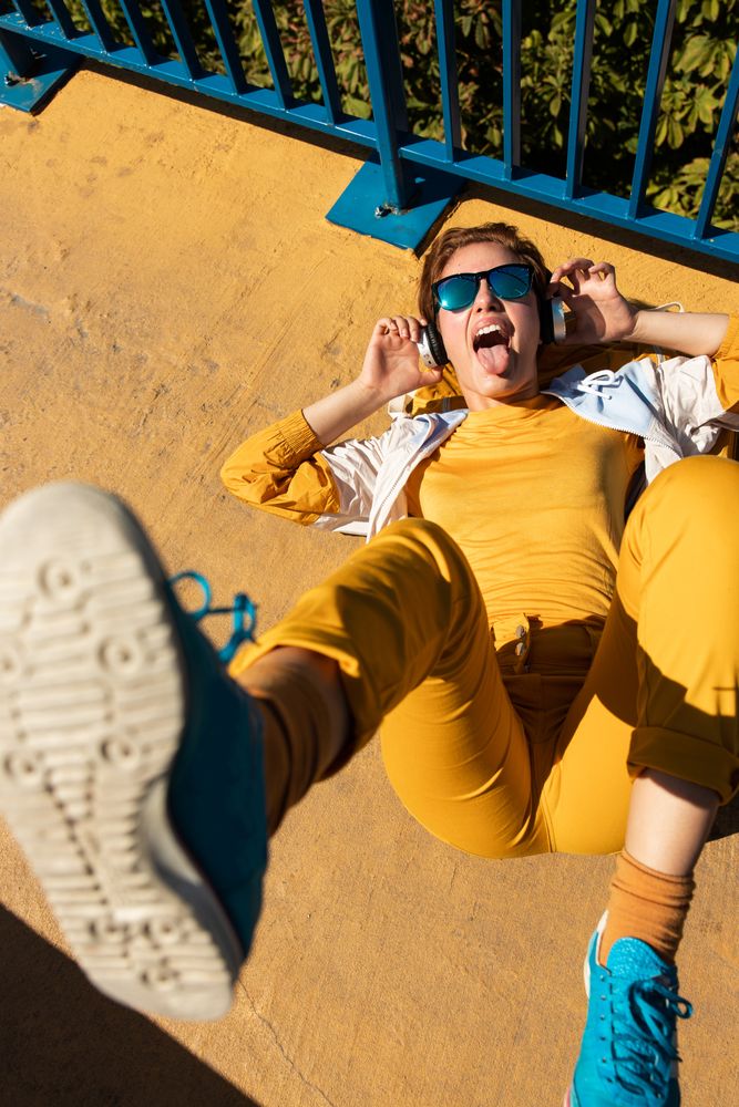 Stylish young woman in vibrant clothes enjoying music on street