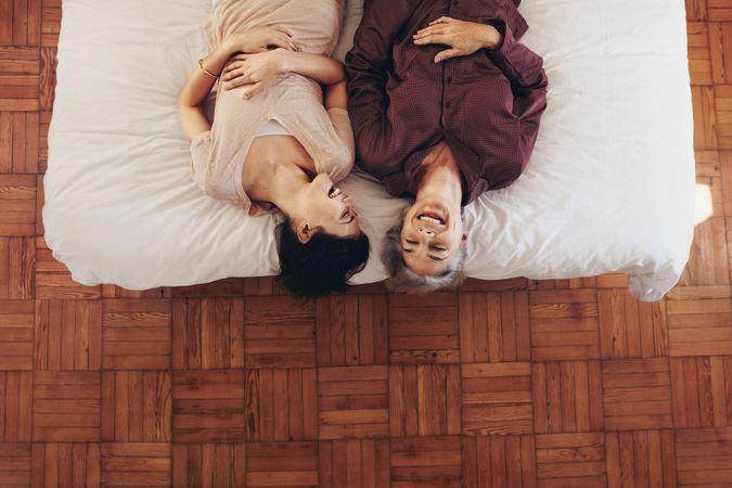 Mother and daughter lying on bed smiling with upside down perspective