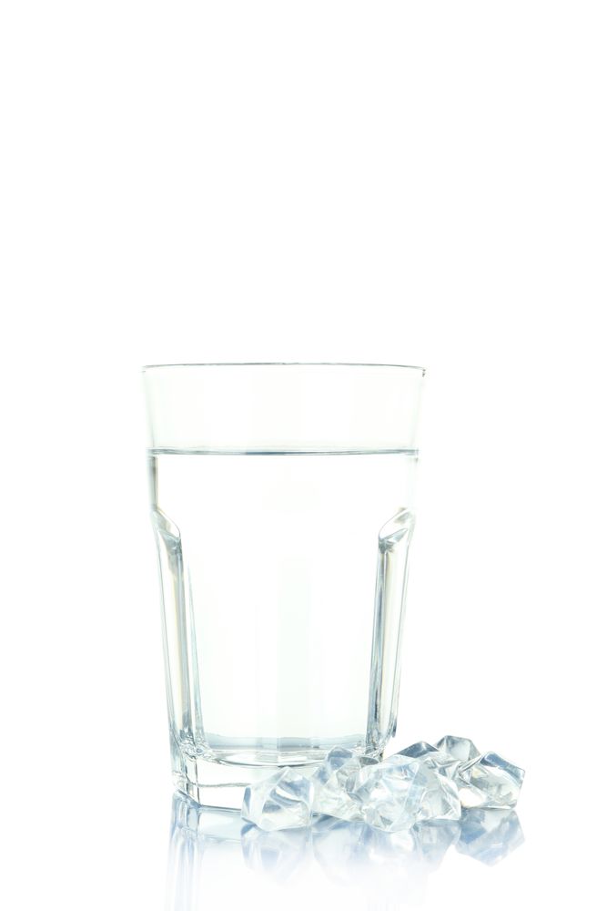 Tall glass of water with ice outside on table