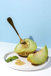 Sliced small melon on plate with spoon and fork