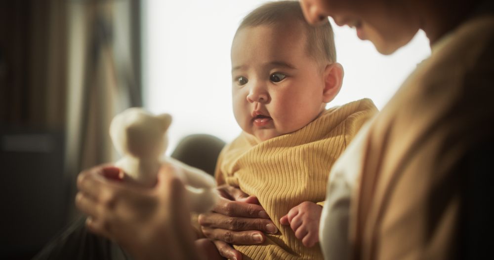 Mother and Baby Bonding Moment: Authentic Shot of an Asian Woman New to Motherhood Playing with her Cute Child in the Peaceful Morning at Home.