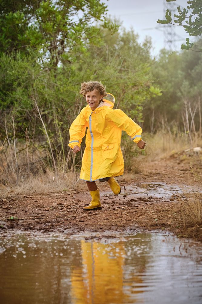 Little boy in raincoat running in countryside