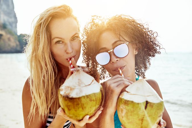 Two women drinking a tropical cocktail on the beach