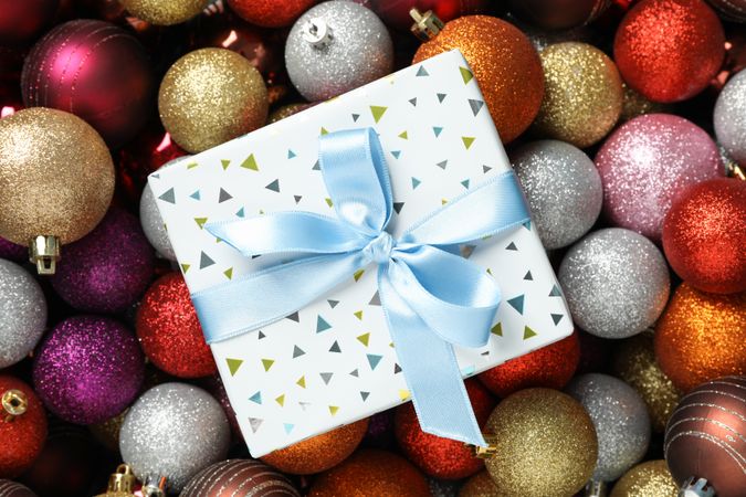 Present on christmas balls background, top view